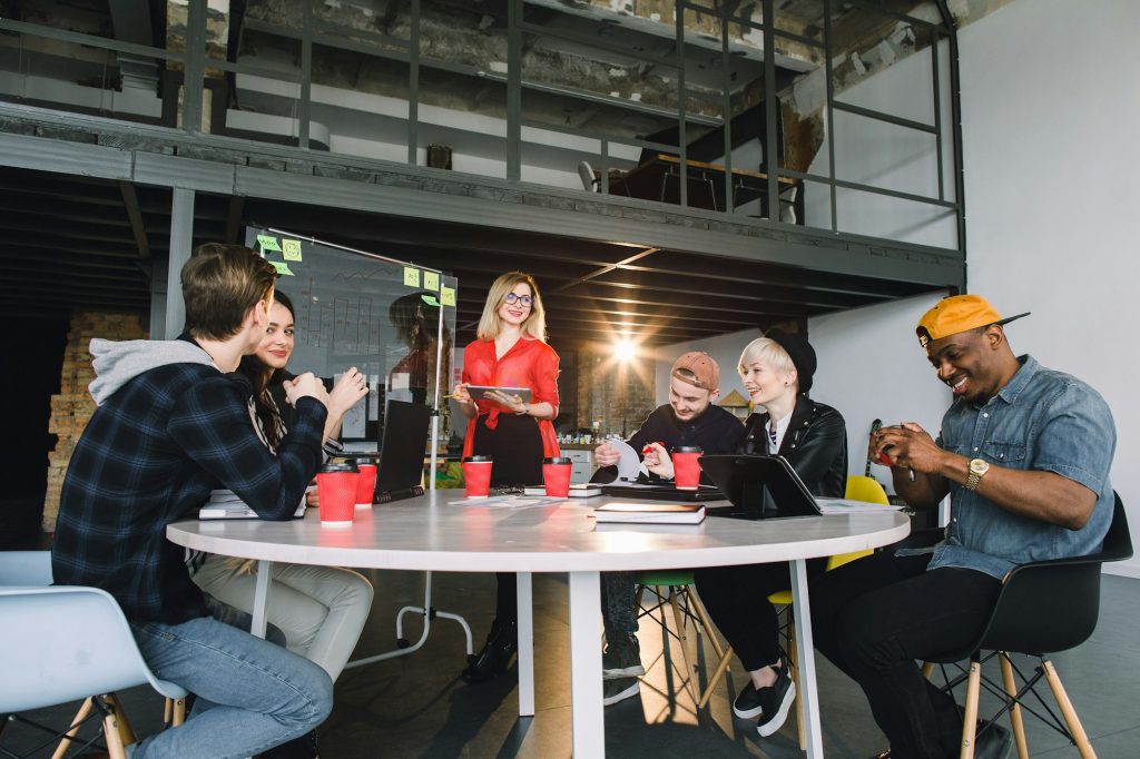 portrait of young business woman in red shirt at modern startup office interior, team in meeting